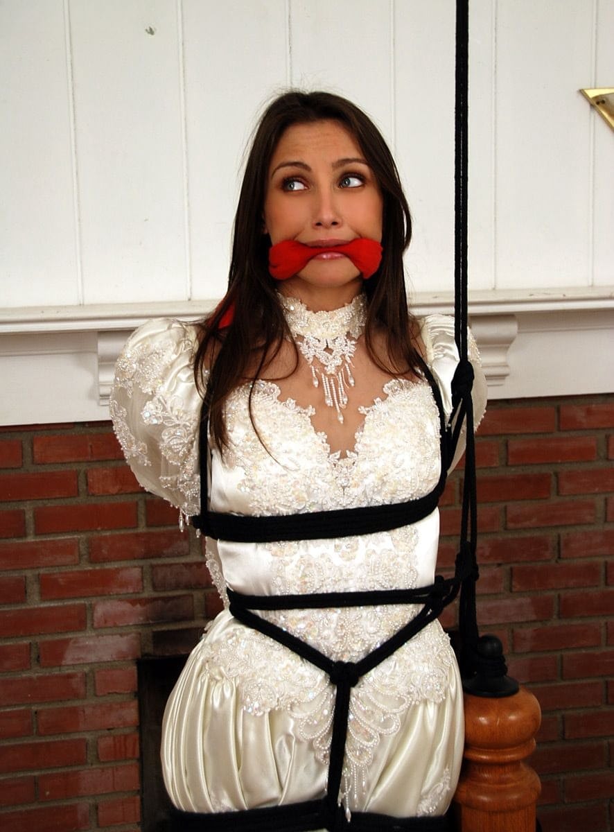 Brunette bride Celeste Star is ballgagged and tied up in her wedding dress