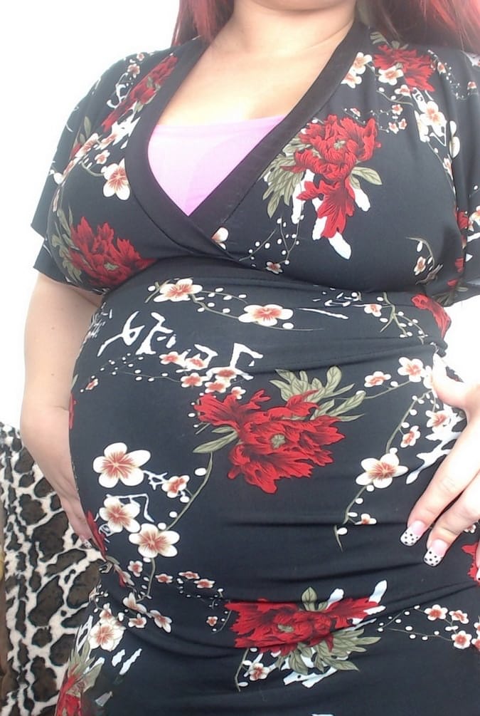 Pregnant redhead Georgia Peach takes her dress off and poses naked on the sofa