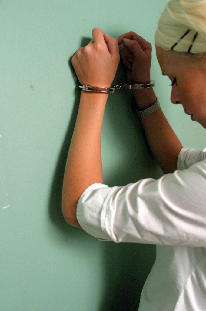 Blonde girl in a black skirt and white blouse is placed in handcuffs