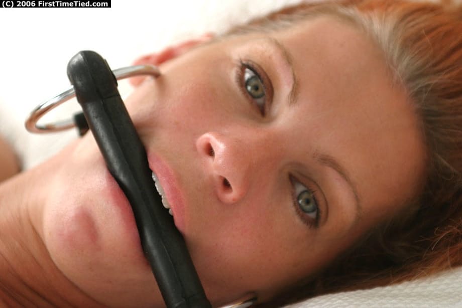 Naked amateur model is tied to a bed with a horse bit in her mouth