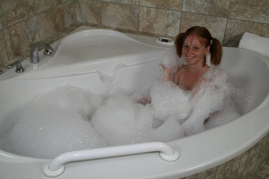 Young looking redhead Alyssa Hart jerks off her stepfather in the bathtub
