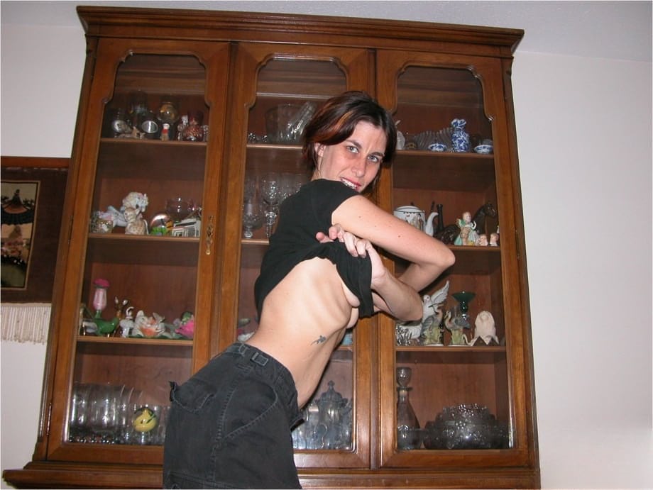 Skinny older lady with an ugly face parts her pussy lips while getting naked