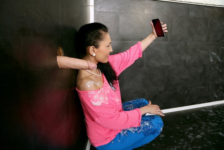 Clothed brunette takes selfie of a cock shooting jizz on her via glory hole