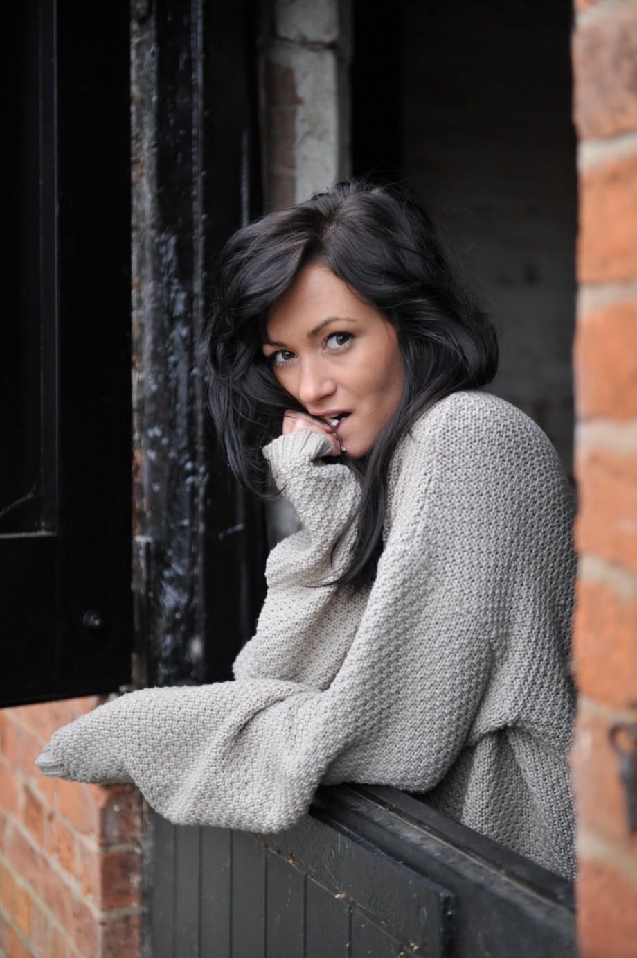Dark haired female exposes her pussy afore a window in black boots