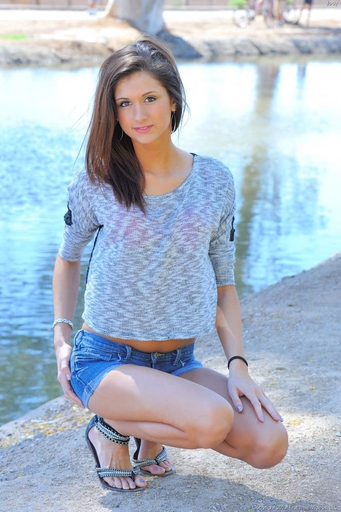 Slender girl in denim shorts stripping naked outdoors on public sidewalk