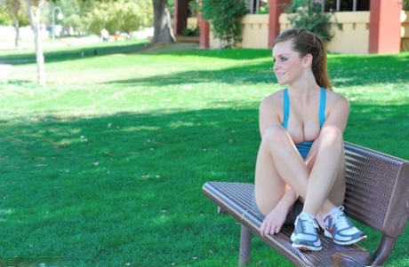 Fitness girl in shorts undressing to show her big tits outdoors
