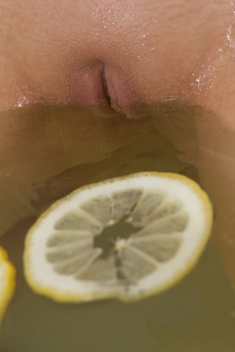 Cute blonde teen sinks her bald twat into a tub filled with lemon slices