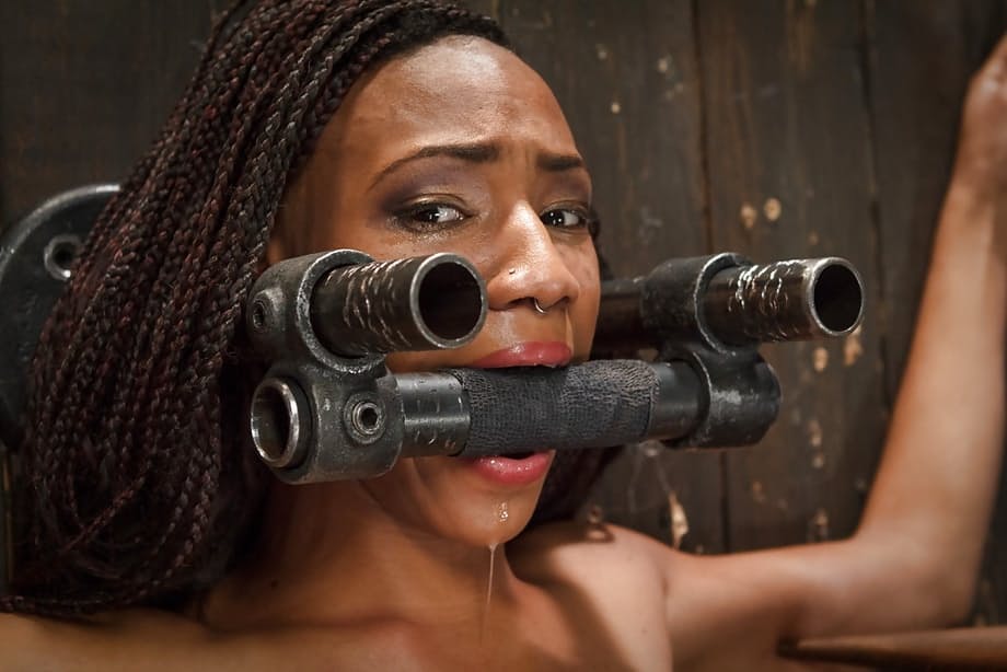 Black submissive Nikki Darling struggles against restraints in BDSM shoot