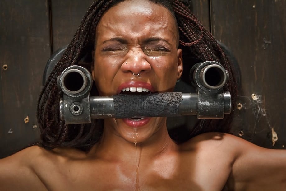 Black submissive Nikki Darling struggles against restraints in BDSM shoot