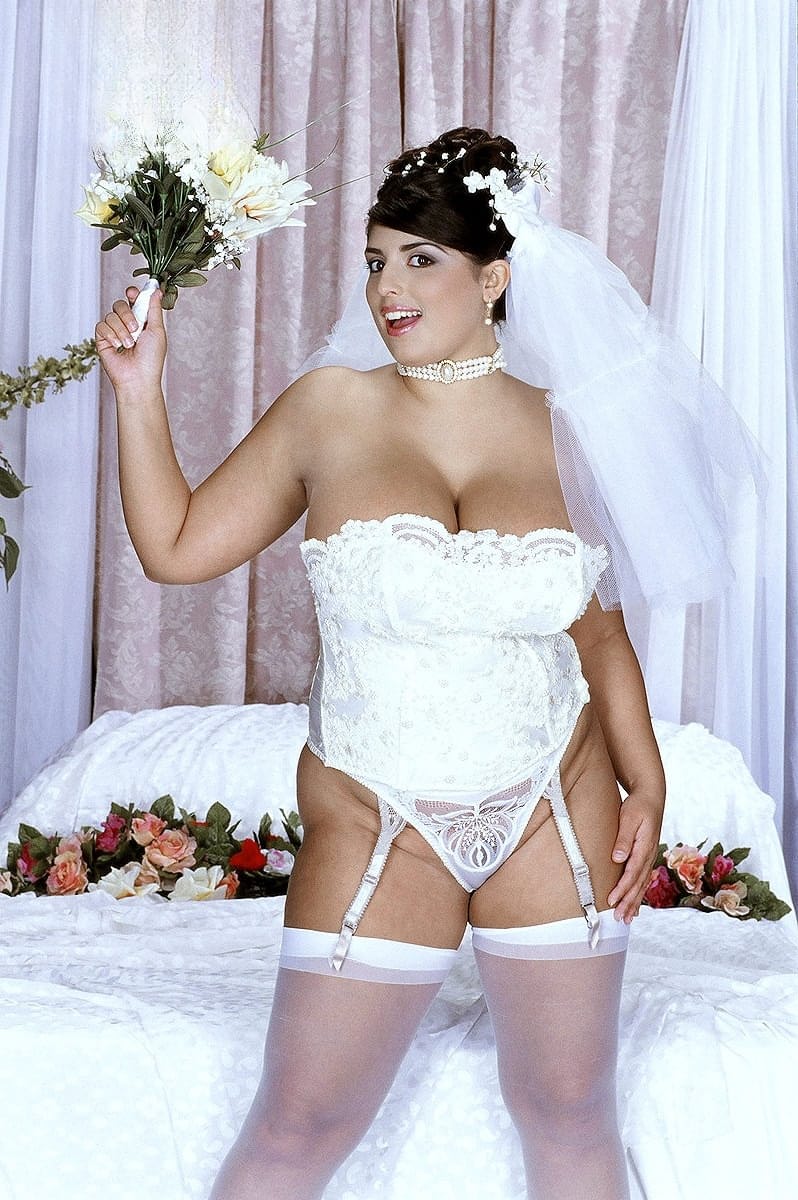 Solo model Kerry Marie unveils her big tits and pussy on a bed in bridal wear