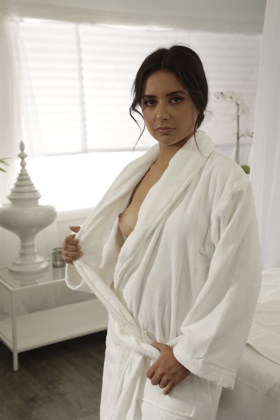 Sweet girl removes a bathrobe to get naked on top of a massage table