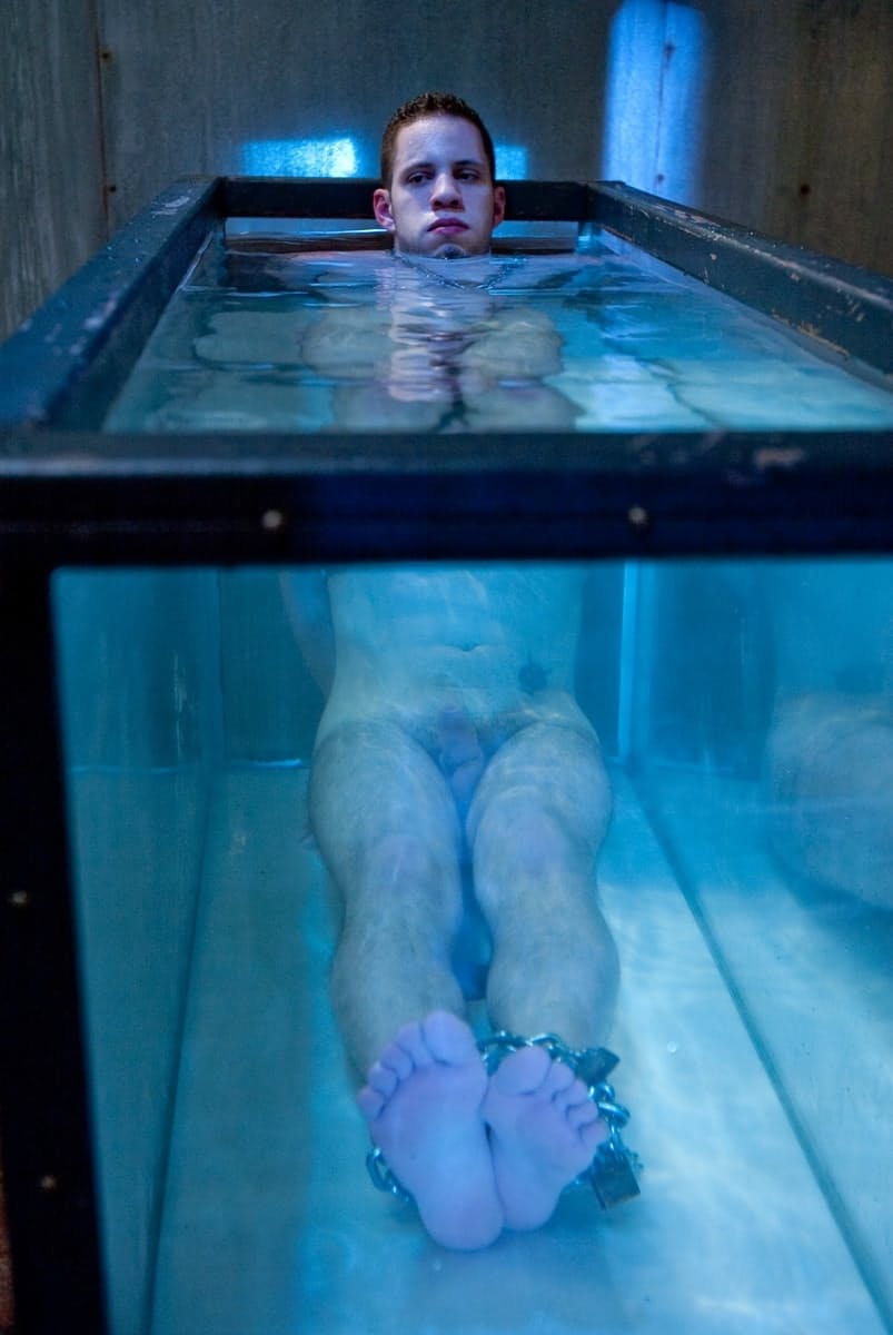 Goddess Isis Love playing with a chained BDSM male sub's cock under the water