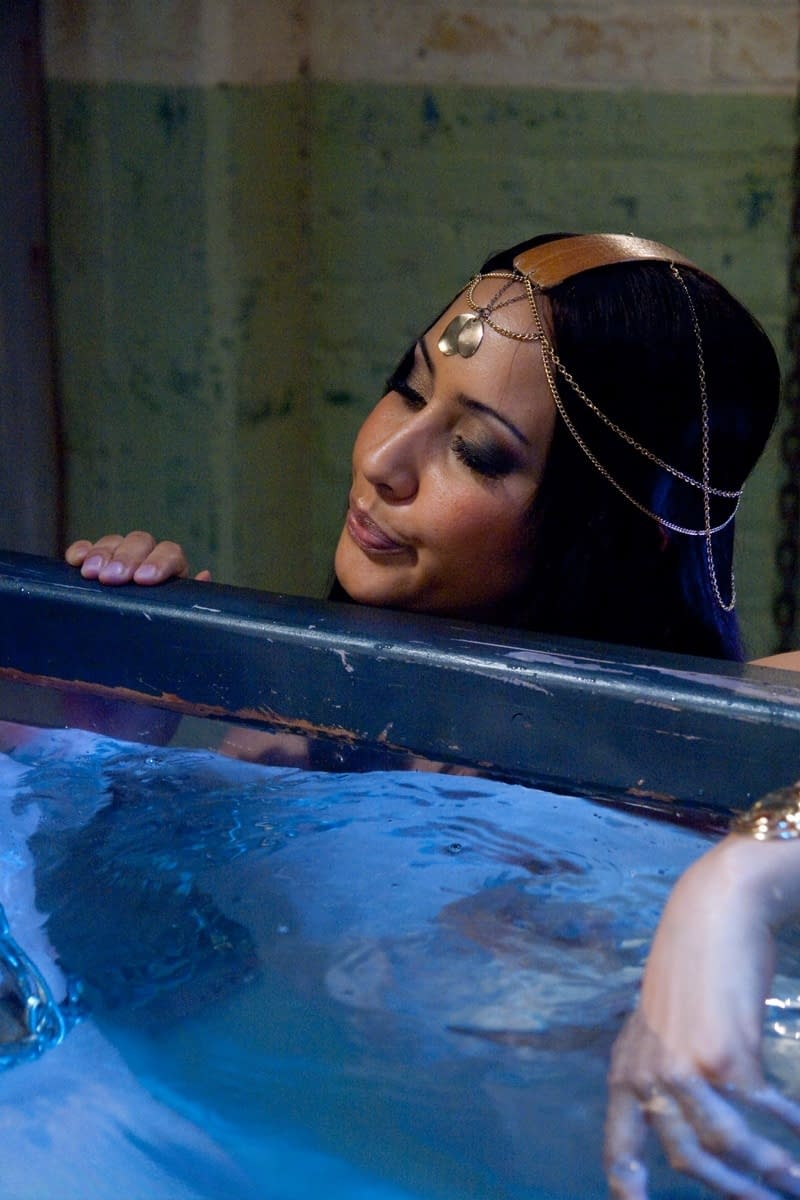Goddess Isis Love playing with a chained BDSM male sub's cock under the water