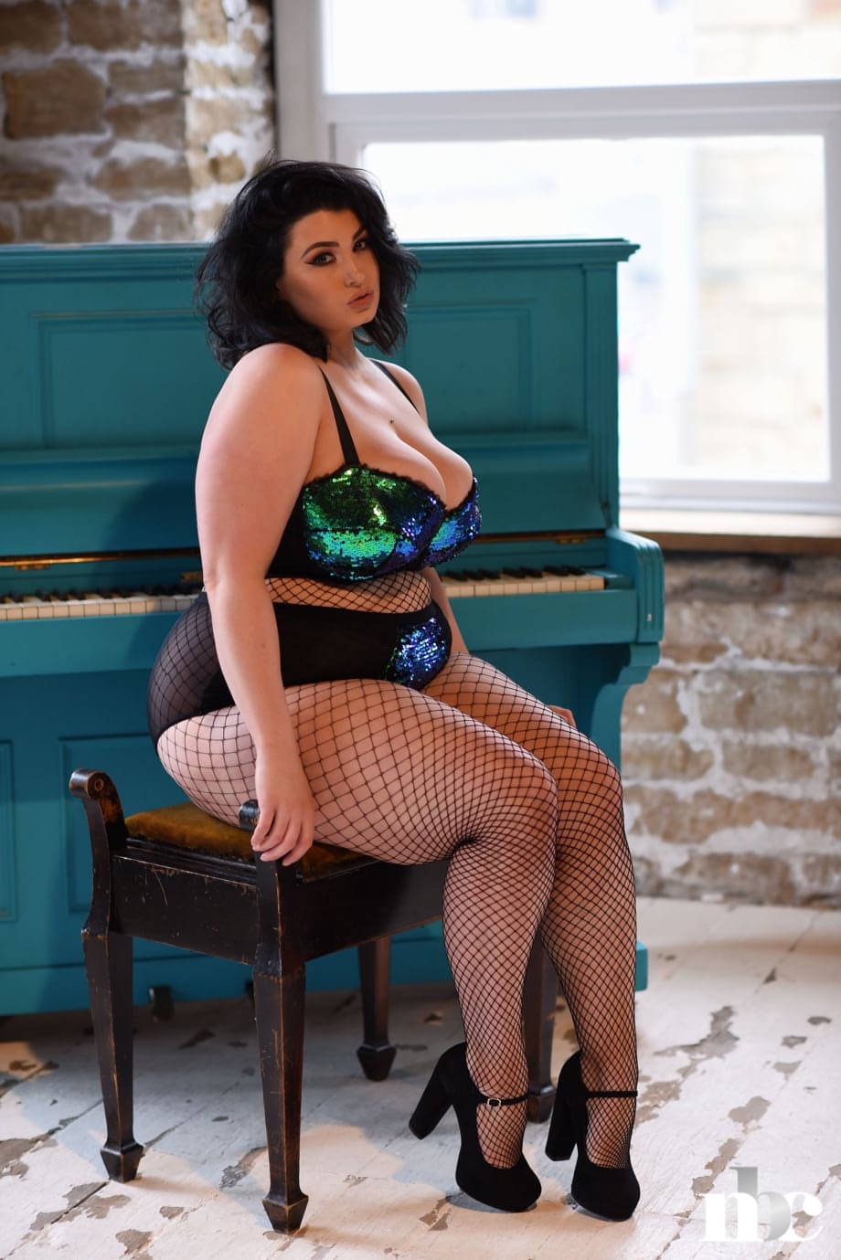 Chubby brunette Kiki uncovers her big tits while posing in fishnets