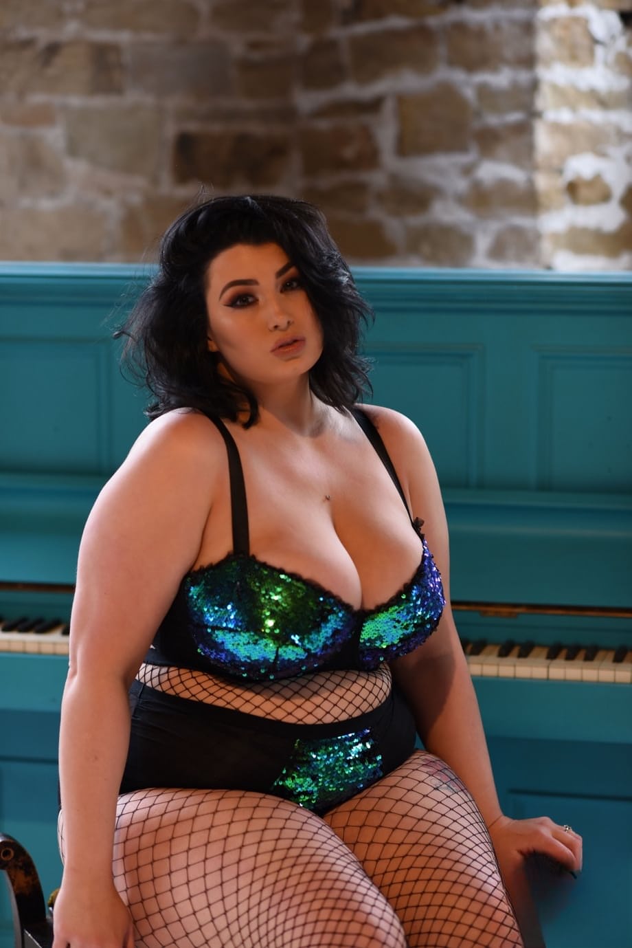 Chubby brunette Kiki uncovers her big tits while posing in fishnets