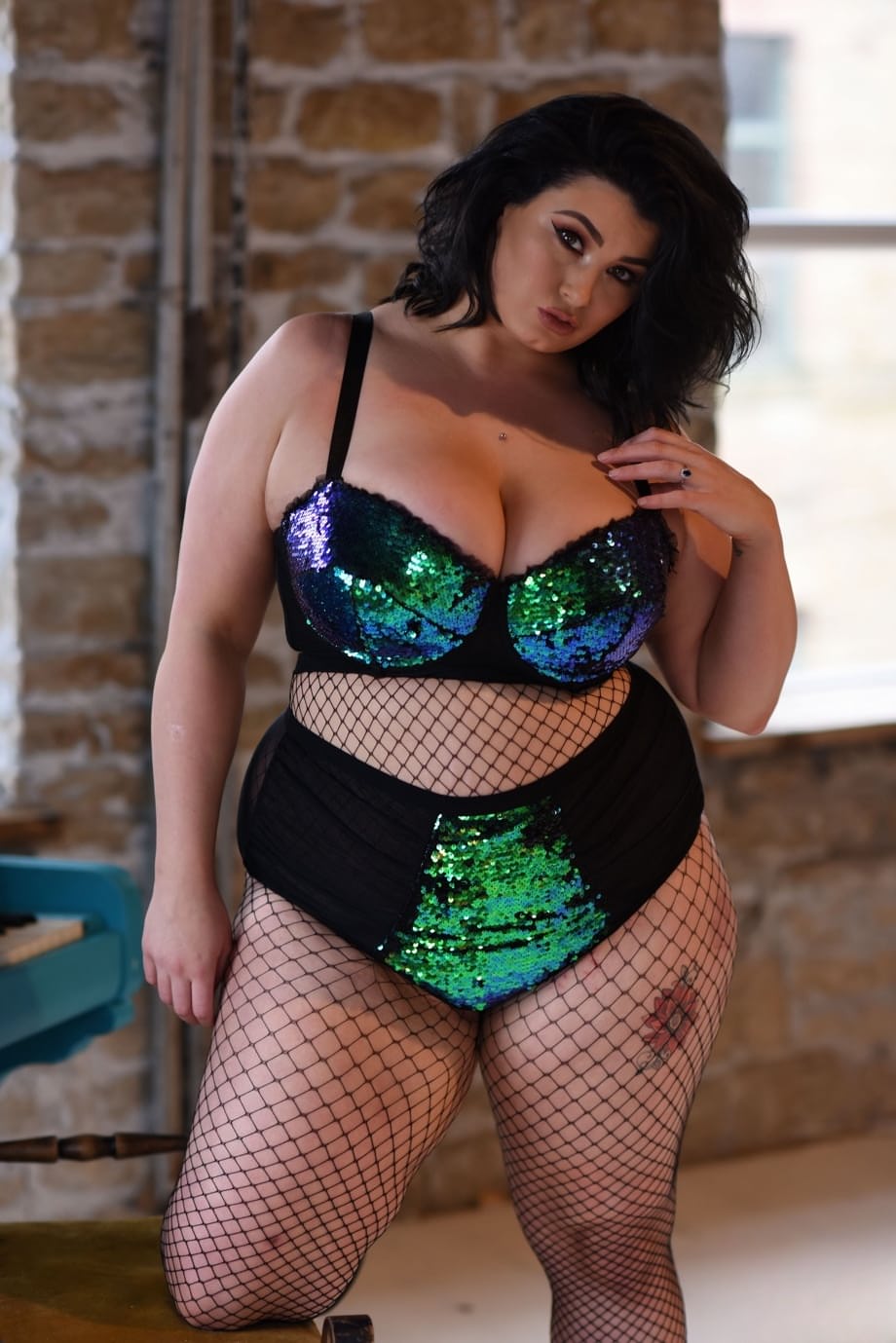 Chubby brunette Kiki uncovers her big tits while posing in fishnets