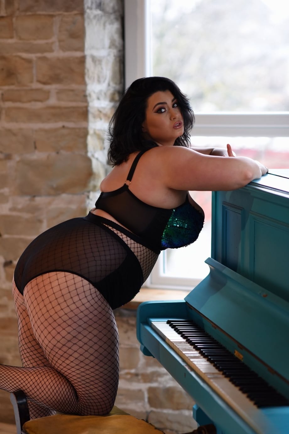 Chubby brunette Kiki uncovers her big tits while posing in fishnets
