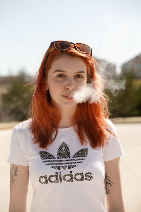 Smoking redhead babe Wanda Ablee uncovers her big tits in the forest