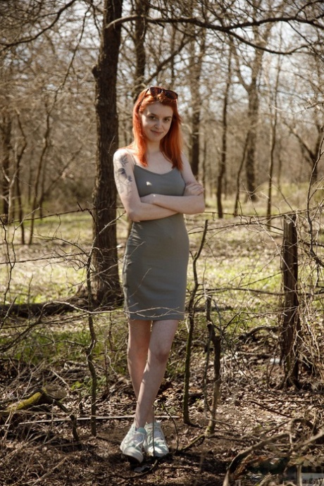 Smoking redhead babe Wanda Ablee uncovers her big tits in the forest