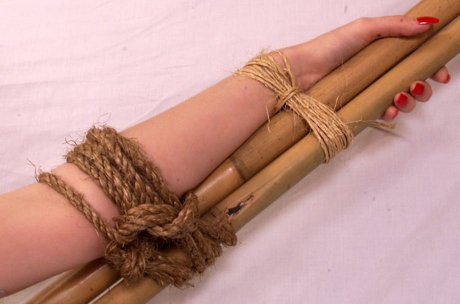 Busty blonde is tied naked and spread eagle style to a bamboo frame