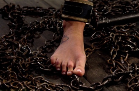 Gagged slave Charlie Ann cuffed in the pillory for naked BDSM ass whipping