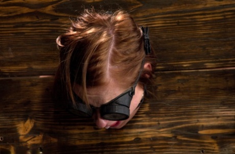 Gagged slave Charlie Ann cuffed in the pillory for naked BDSM ass whipping