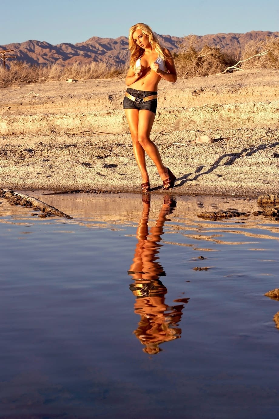Slender centerfold Kayden Kross strips her clothing to squat naked in the sand