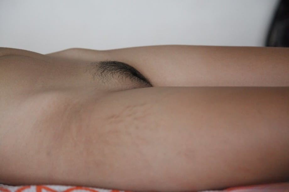 Skinny Asian spinner Lynn displays her small tits and innie pussy on the bed