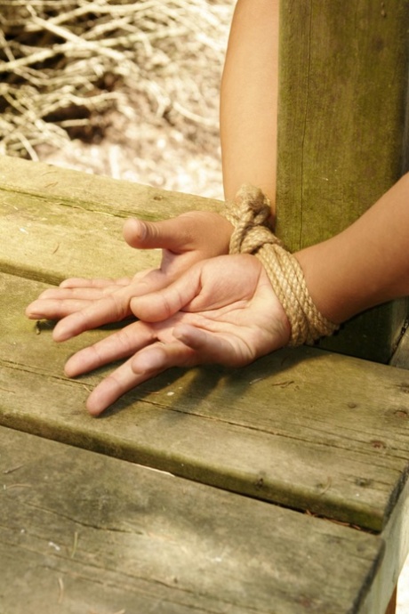 Blonde chick is left bound and gagged to a wooden structure in the woods