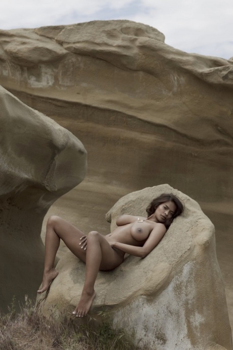 Exotic and adorable brunette Clarencia Niamat poses naked on the rock ground