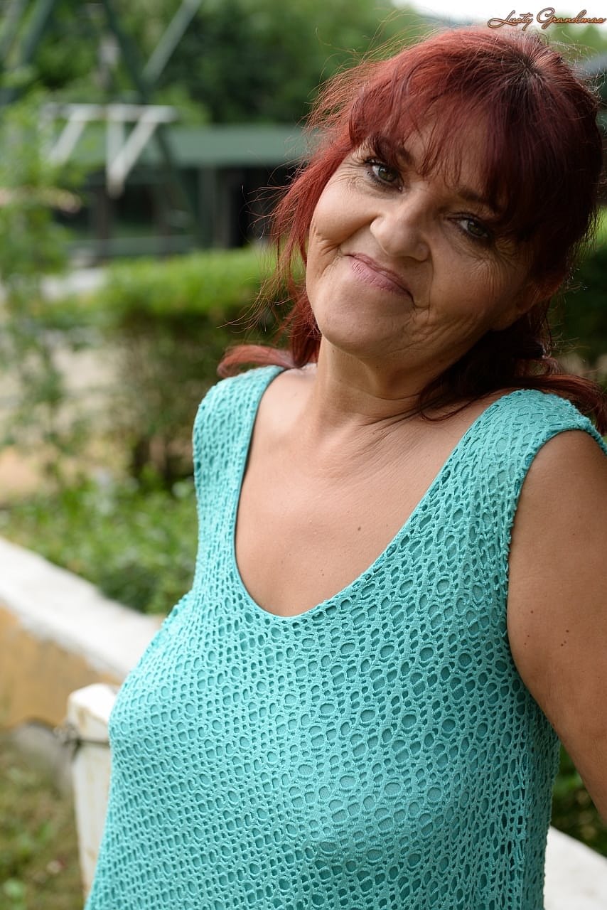 Redhead granny Livia lifts her blue dress up and reveals big natural tits