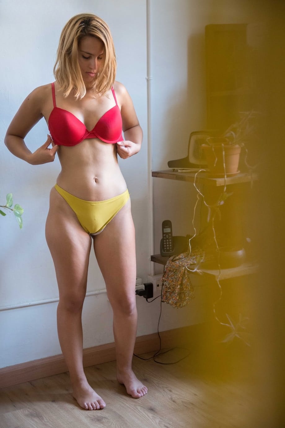 Naked white chick pulls on her bra and panties as she gets dressed
