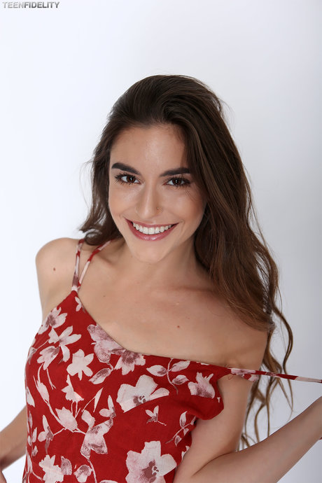 Pretty brunette Arielle Faye strips short dress to model tiny tits in thong