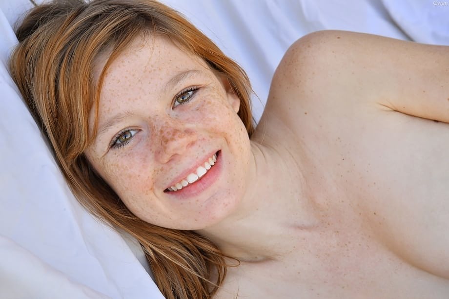 Young redhead Mia Collins takes a butt plug while masturbating on a bed