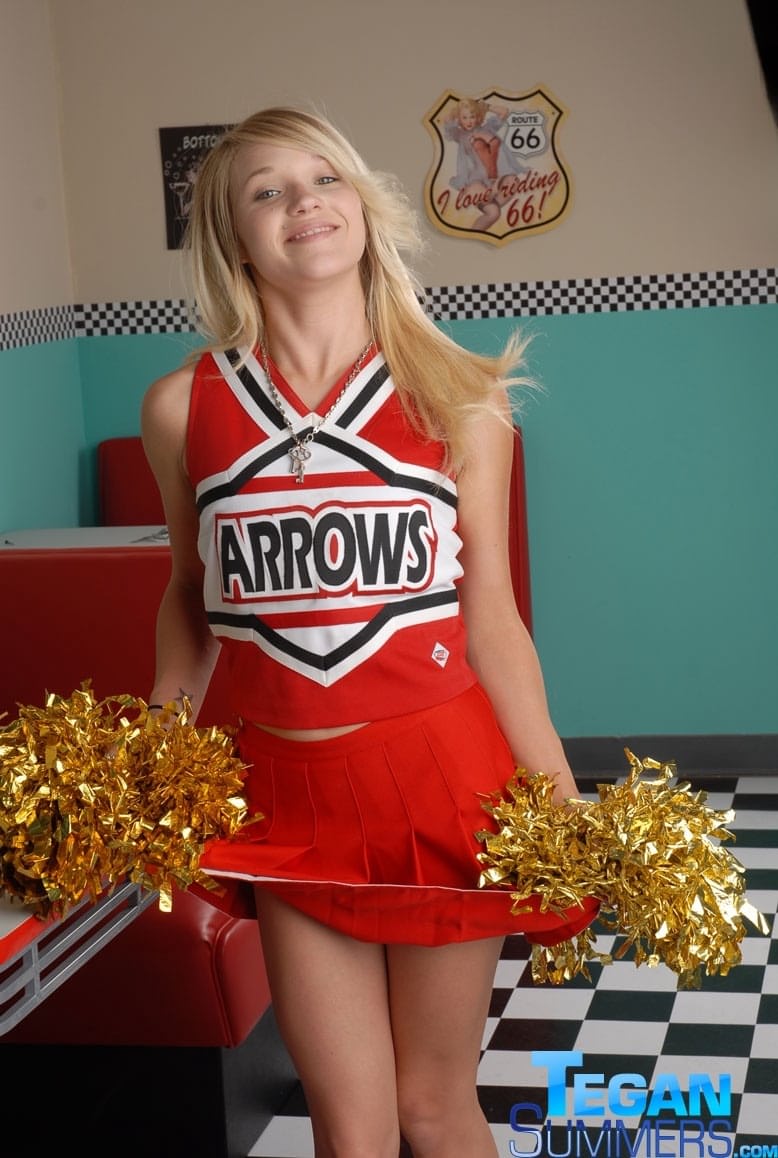 Cute college blonde Tegan Summers poses in a cheerleader outfit at a diner
