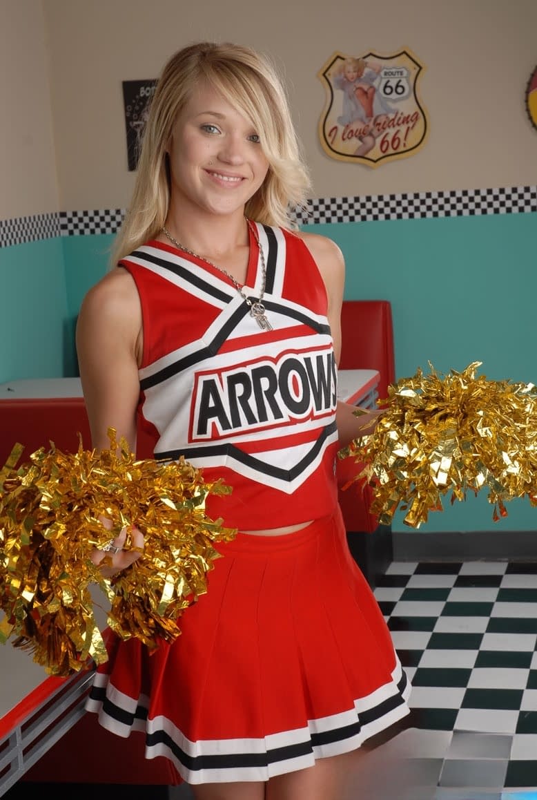 Cute college blonde Tegan Summers poses in a cheerleader outfit at a diner