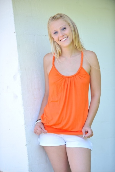 Flexible blonde uncovers her small tits before doing the splits in a yard